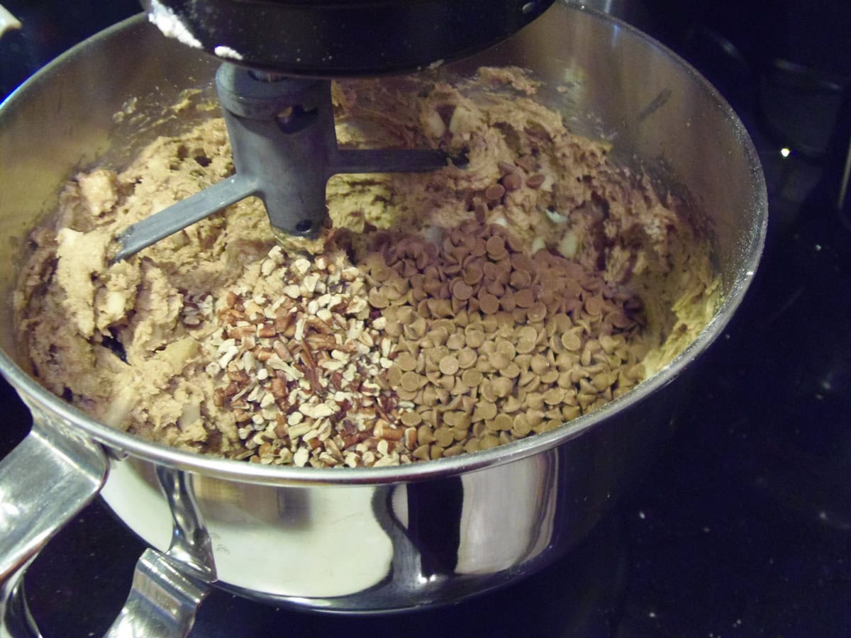 Applesauce muffin batter in a bowl with with chopped pecans and cinnamon chips.