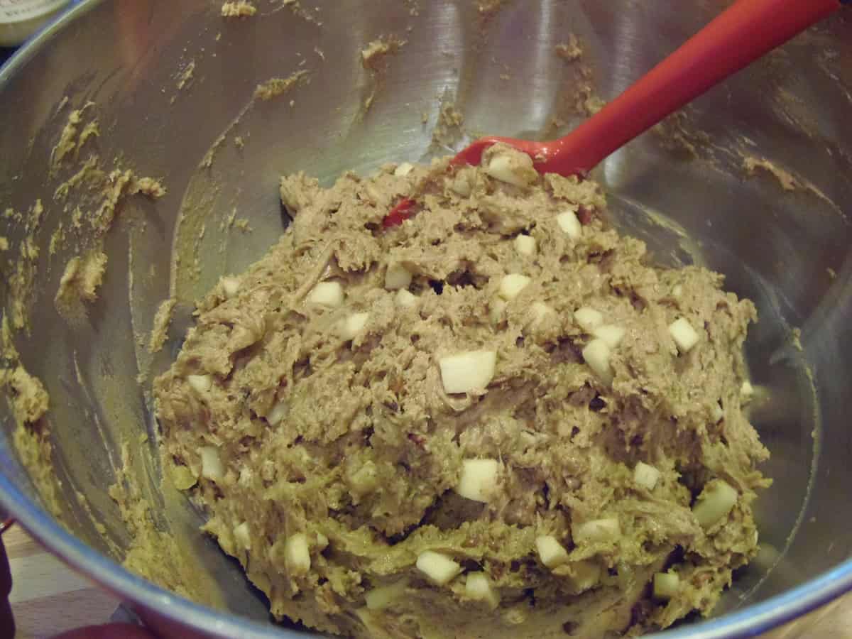 A thick applesauce muffin batter in a bowl with a red spatula.