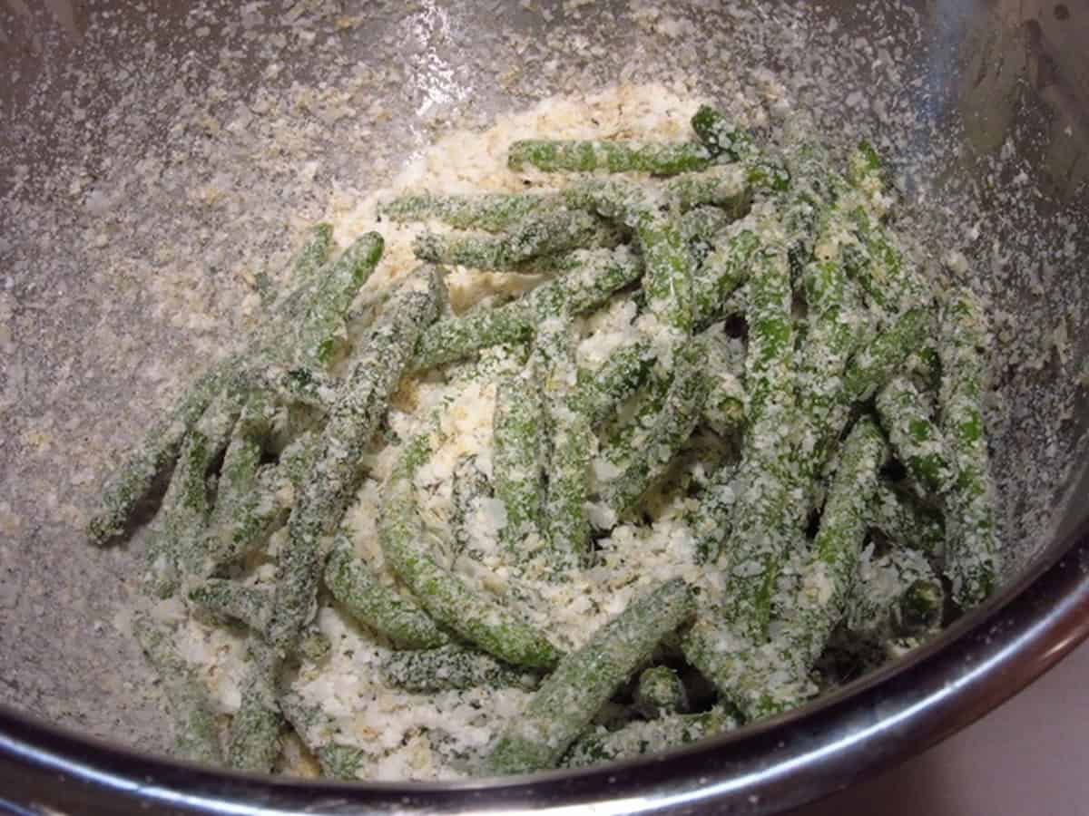 Green beans in a silver bowl along with potato flakes.
