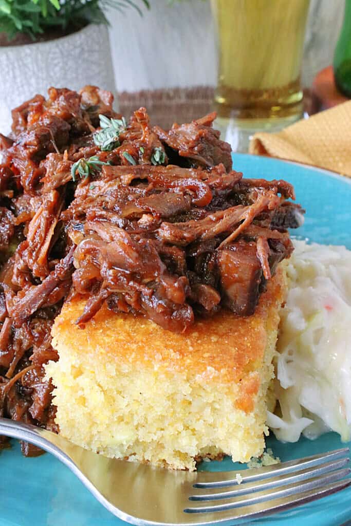 A golden square of cornbread topped with tasty looking pulled beer braised beef brisket.