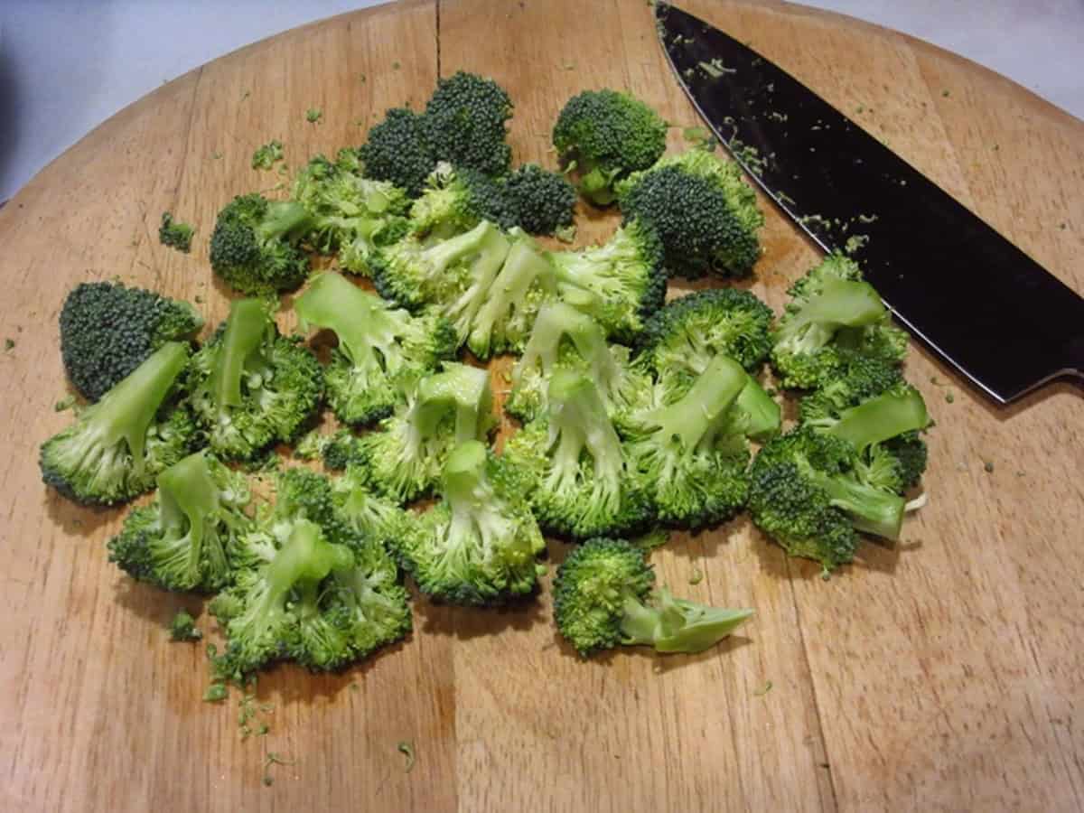 Chopped broccoli on a wooden cutting board.
