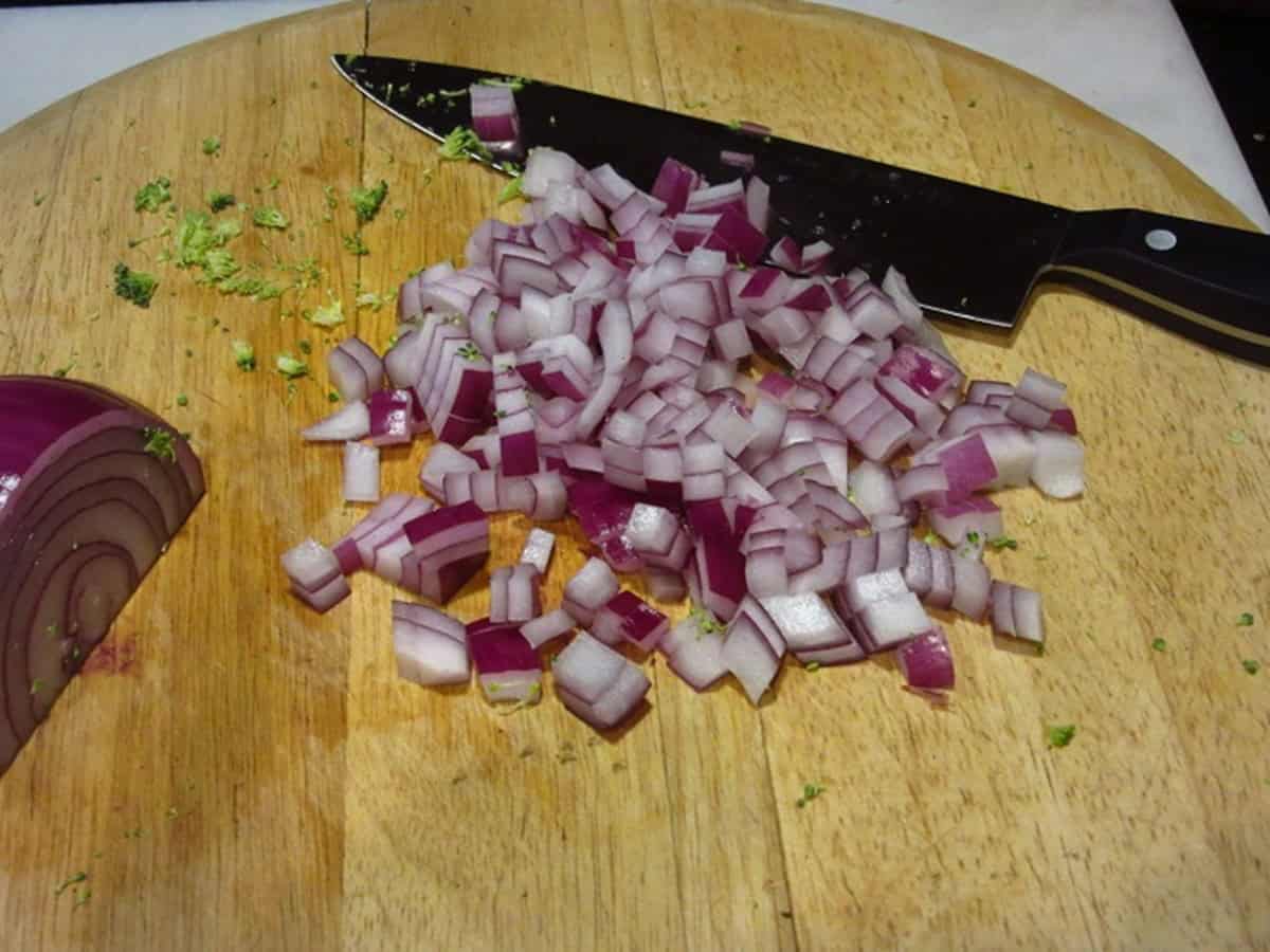 Diced red onion on a cutting board with a knife.