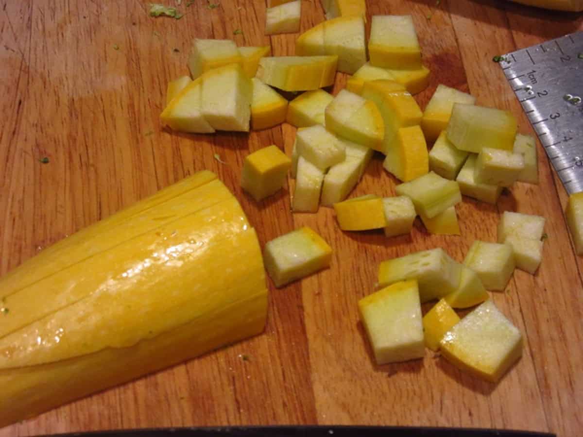 Diced yellow squash on a cutting board.