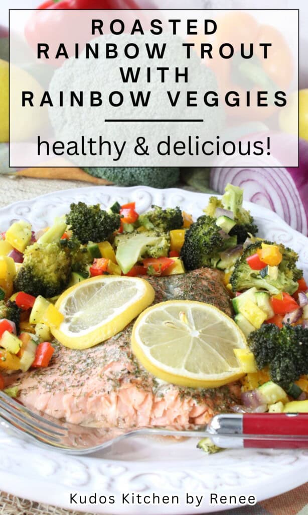 A white dinner plate filled with a serving of roasted rainbow trout with rainbow vegetables along with a red fork.
