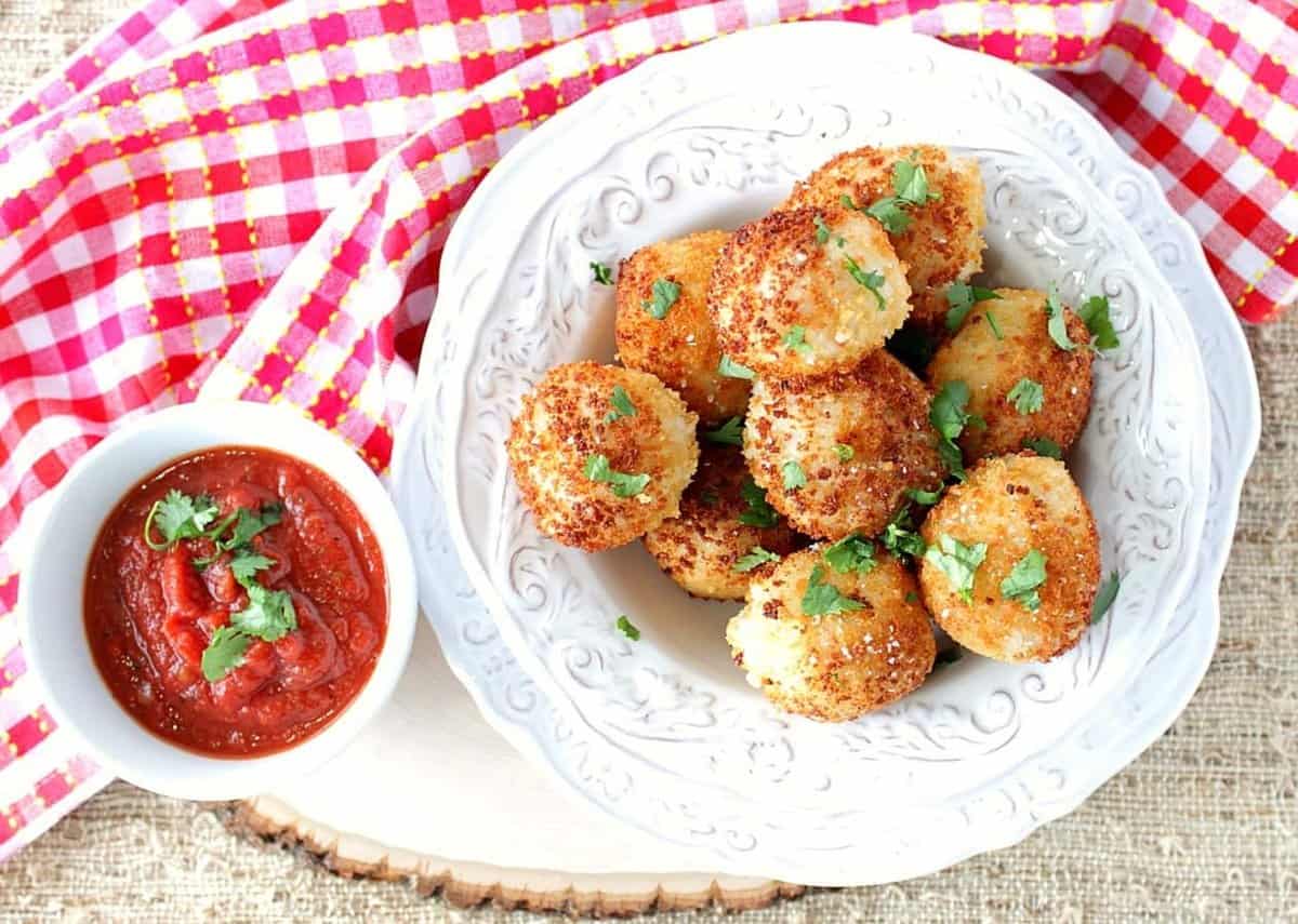A red, white, and yellow napkin underneath a bowl of cooked arancini balls.