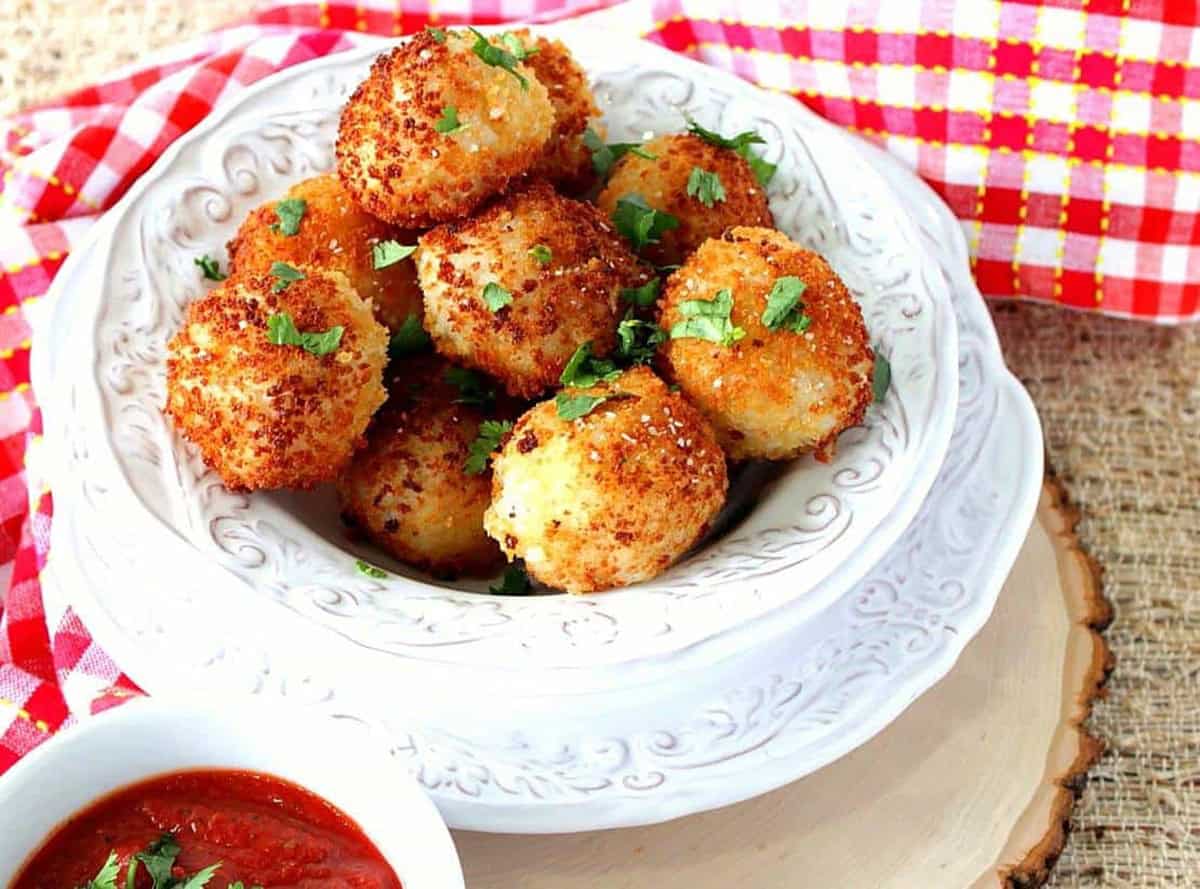 Beautify golden brown arancini balls in a white bowl ready for serving.