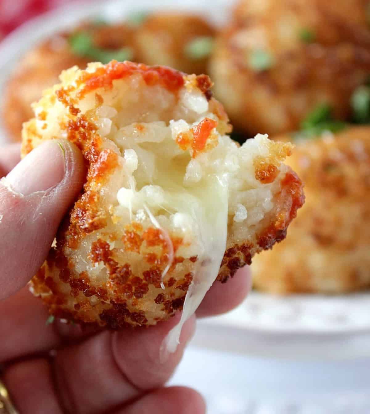 A mozzarella cheese pull from the inside of an arancini ball.
