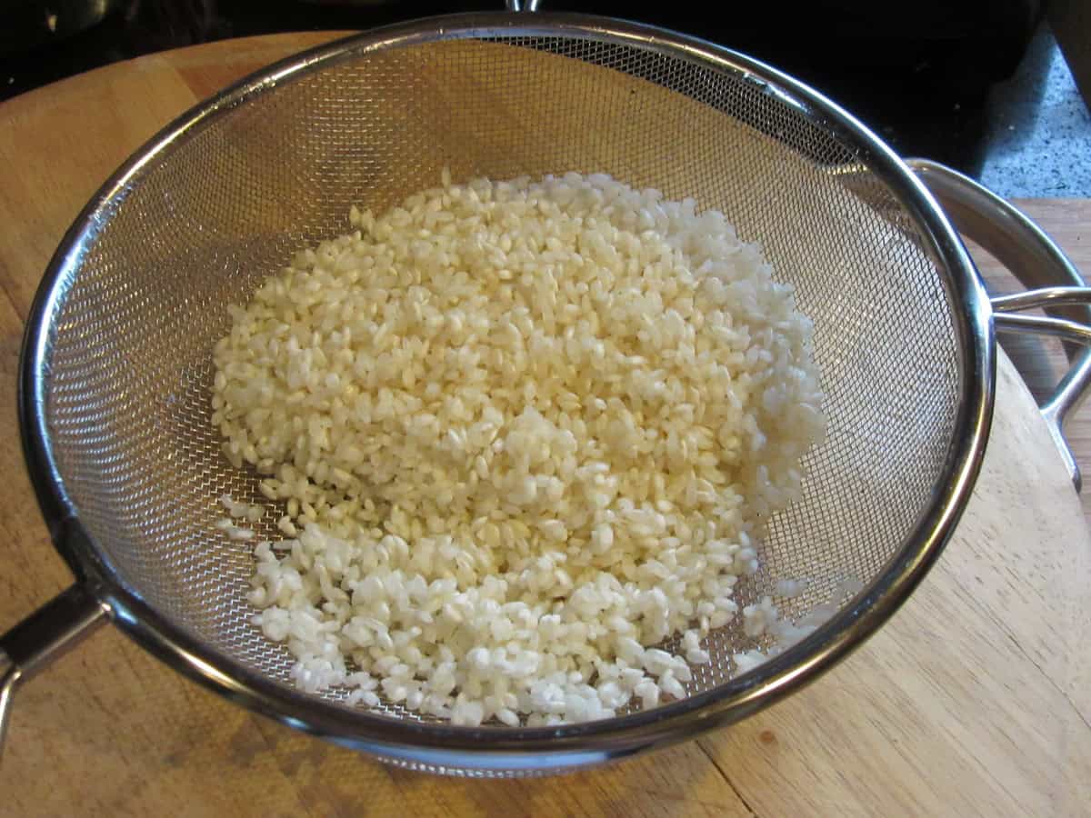 Short grain arborio rice in a strainer.