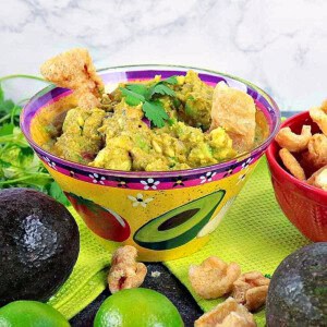 A cute painted avocado bowl filled with homemade guacamole with pork rinds in the guac.