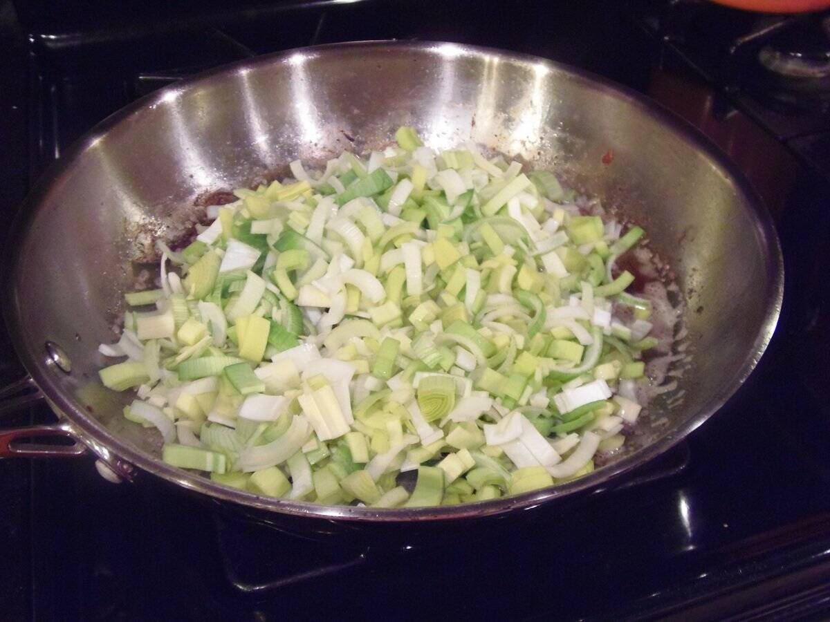 Sliced, uncooked leeks in a large skillet.