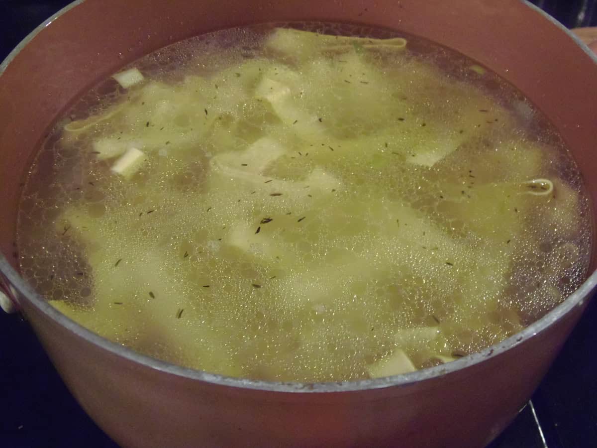 A pot of water with pappardelle pasta cooking inside.