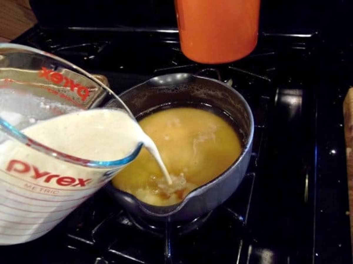 Cream being poured into a saucepan on the stovetop.
