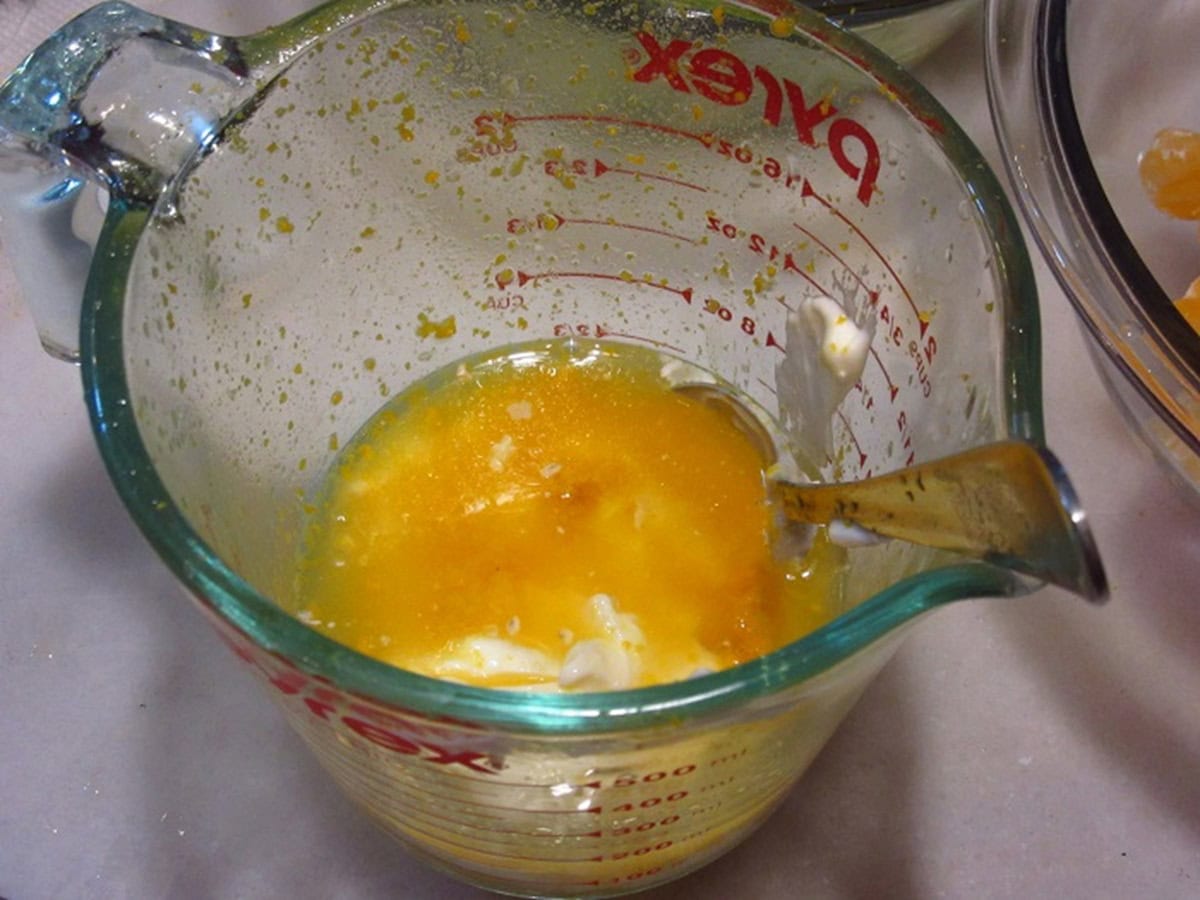 Mayonnaise, orange zest and orange juice in a glass measuring cup.