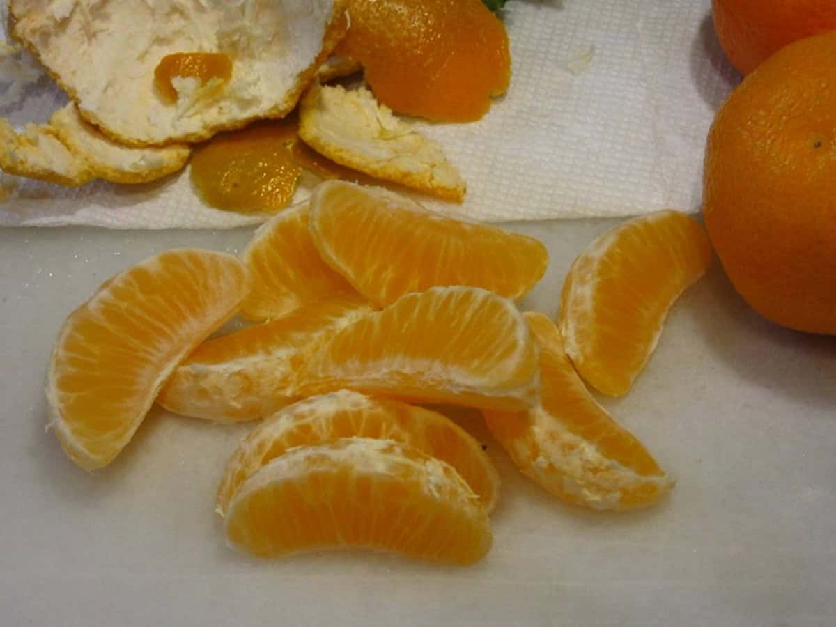 Peeled and segmented mandarin orange pieces on a counter.