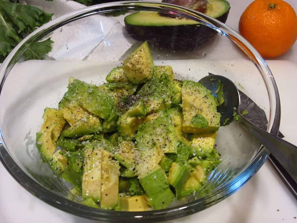 Salt and pepper on a bunch of diced avocados in a bowl.