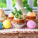 A colorful photo of carrot cake cupcakes surrounded by speckled Easter eggs.