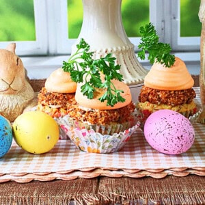 A colorful photo of carrot cake cupcakes surrounded by speckled Easter eggs.