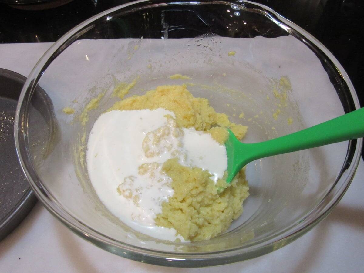 Almond cake batter with heavy cream in a glass bowl.