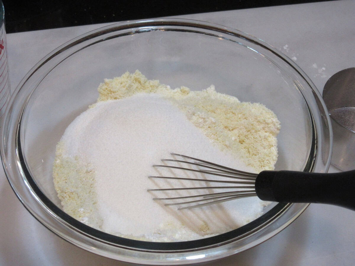 Dry ingredients in a glass bowl along with a whisk.