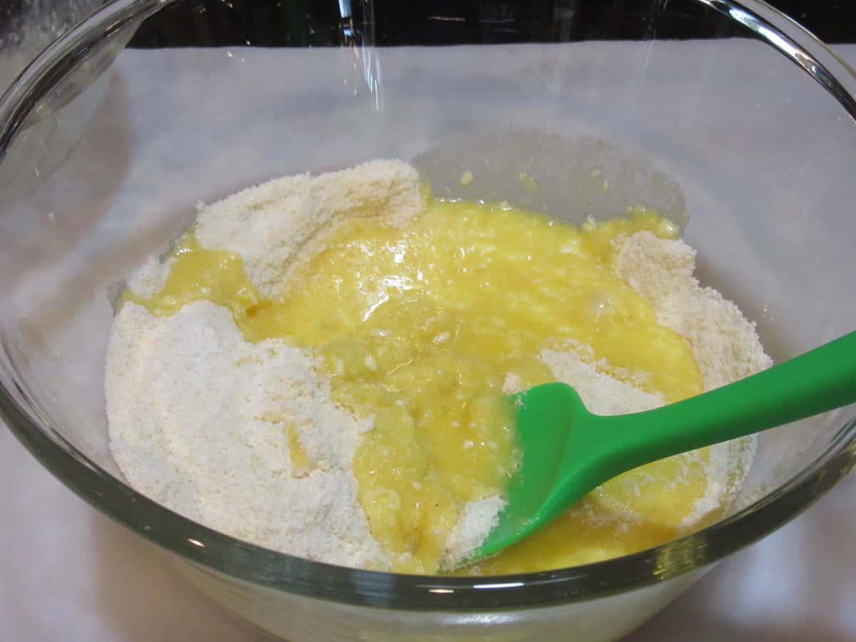 Almond flour and a wet egg mixture in a glass bowl.