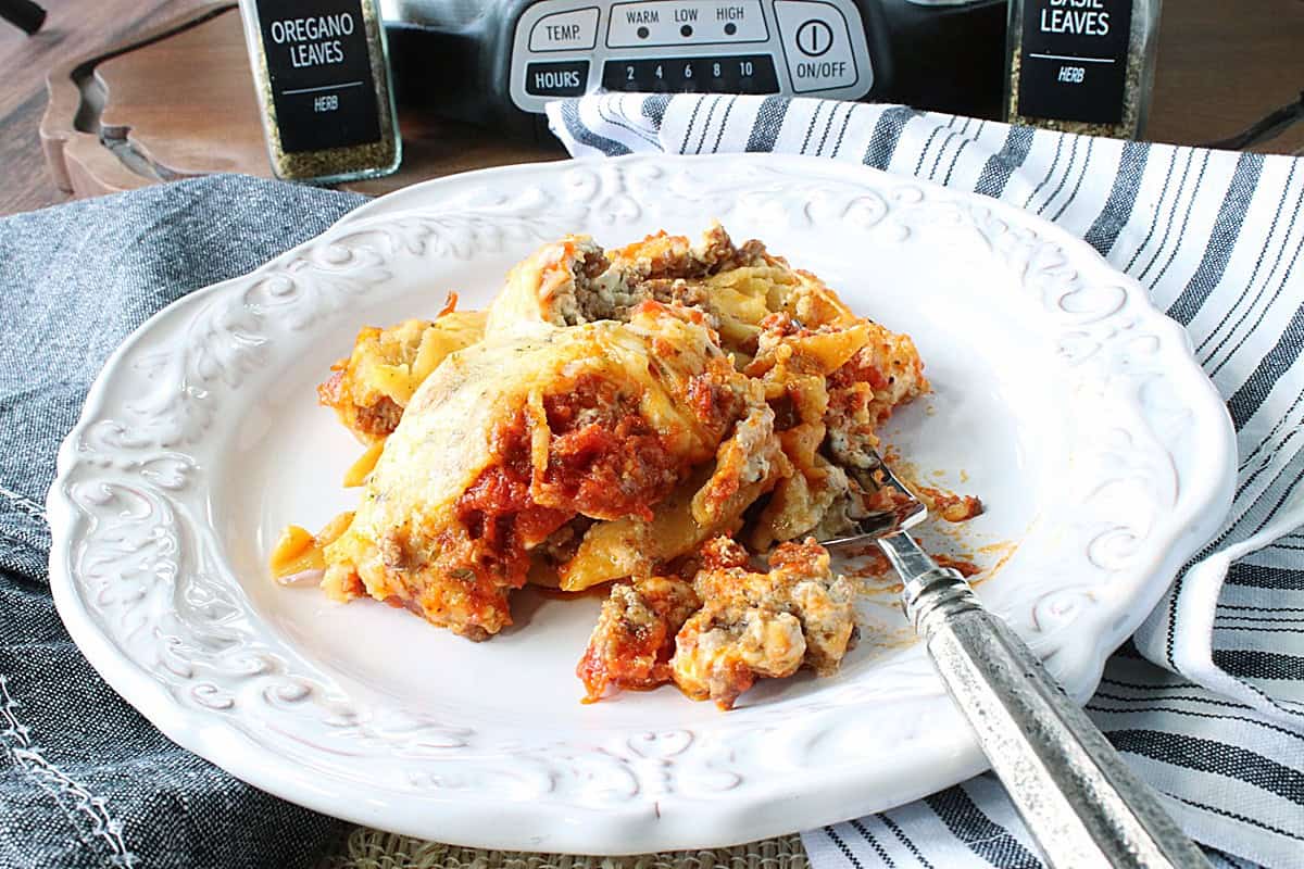 A pretty white plate loaded with a healthy serving of cheesy lasagna with cooked sausage.