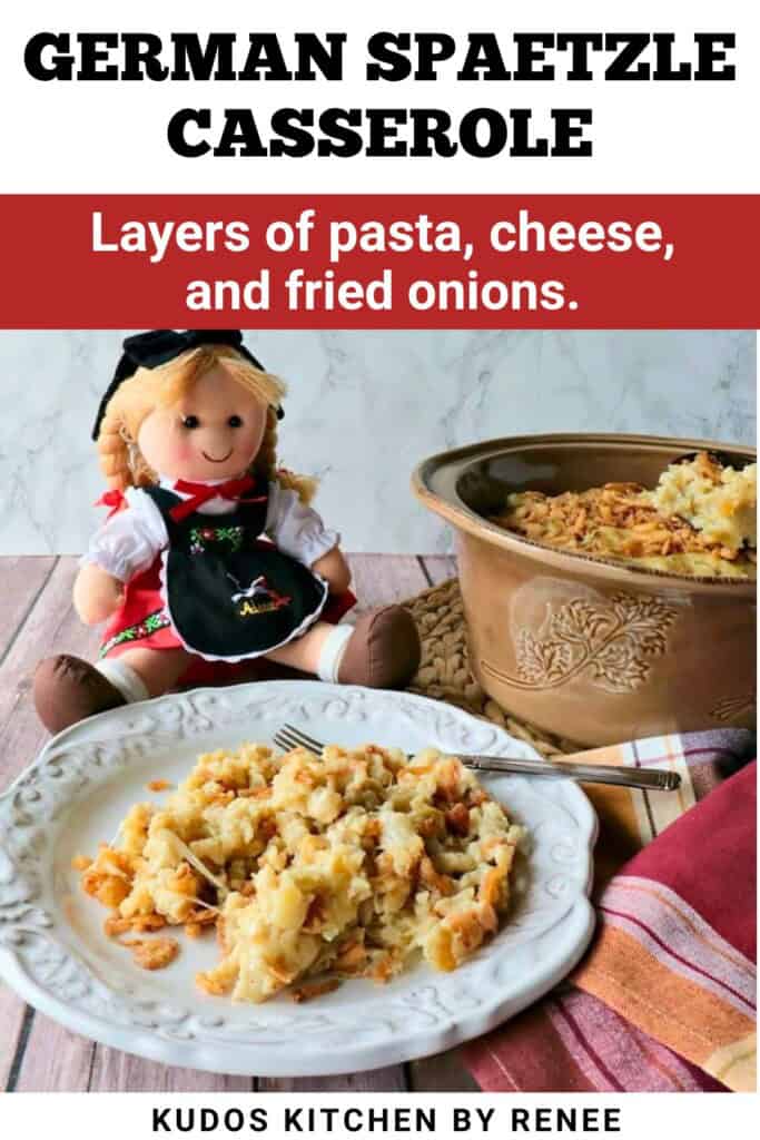A plate with a serving of German spaetzle casserole in the foreground and a little German doll in the background.