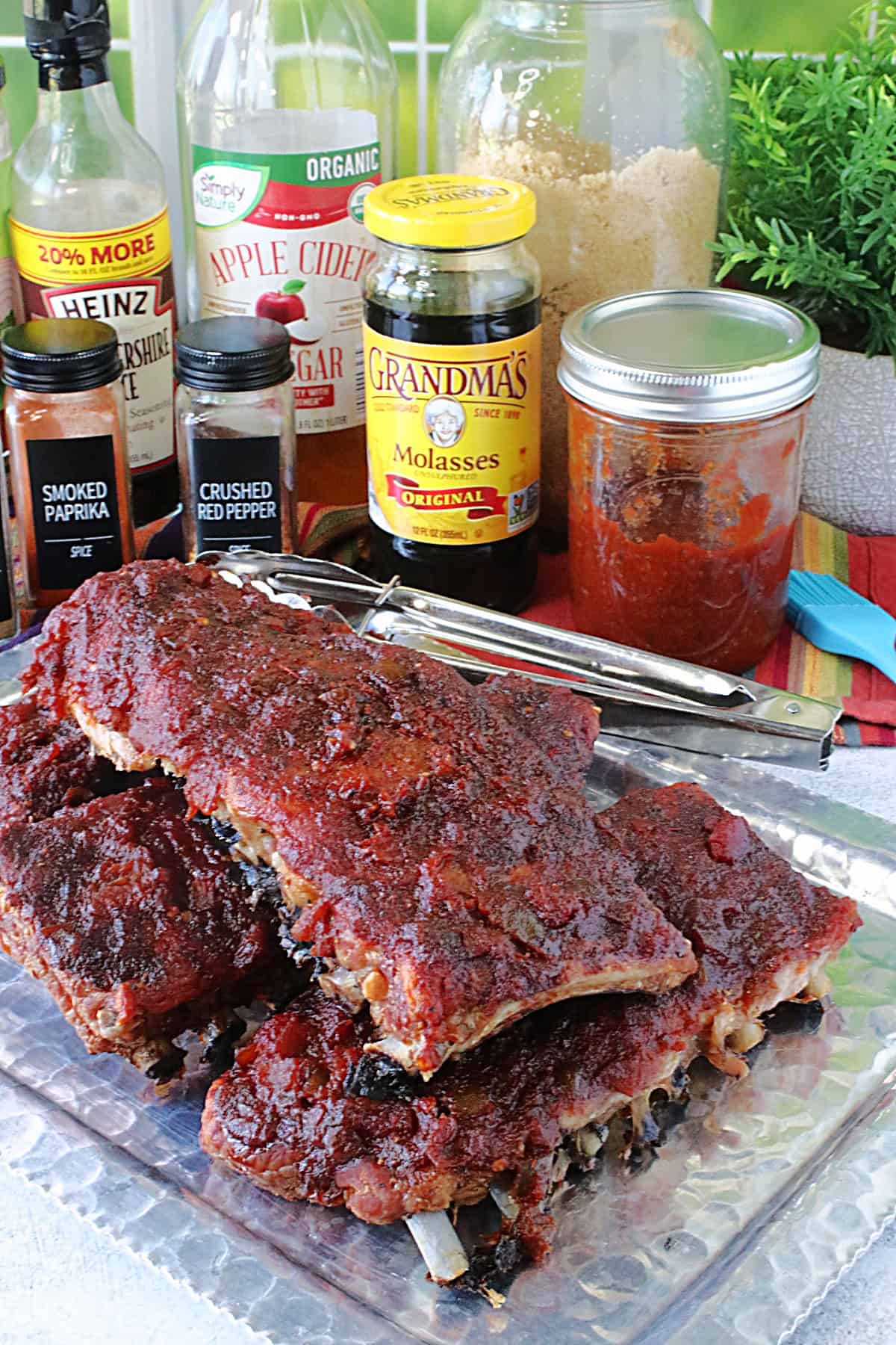 Yummy looking Salsa BBQ Sauce baby back ribs stacked on a silver platter for serving.
