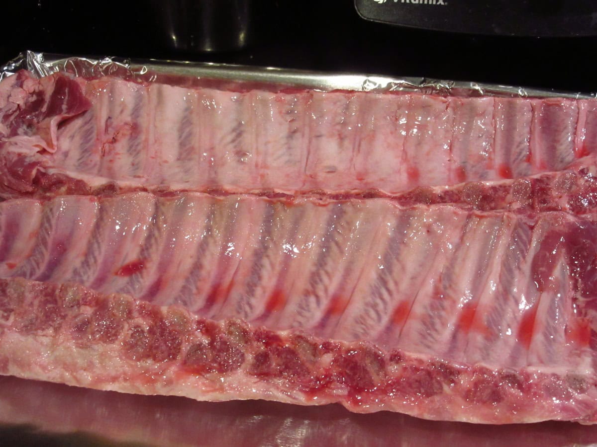 The underside of two slab of pork baby back ribs.