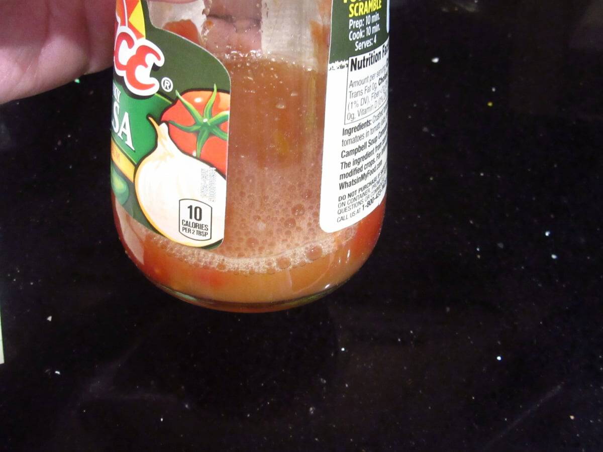 Pineapple juice in the bottom of an empty salsa jar.