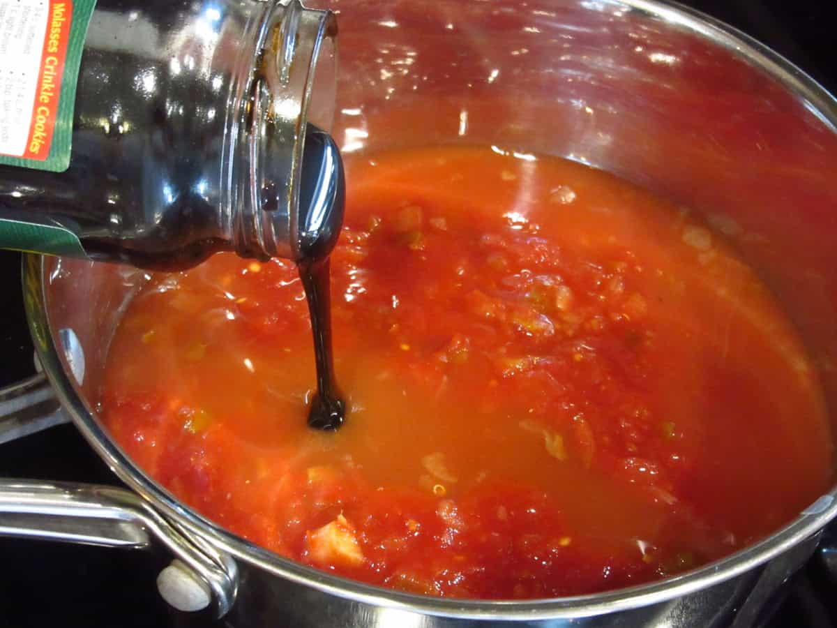 Molasses being poured into a saucepan containing the makings of salsa BBQ sauce.