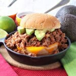 A delicious looking salsa sloppy joe sandwich with melted cheese and avocado slices in a baby cast iron skillet.