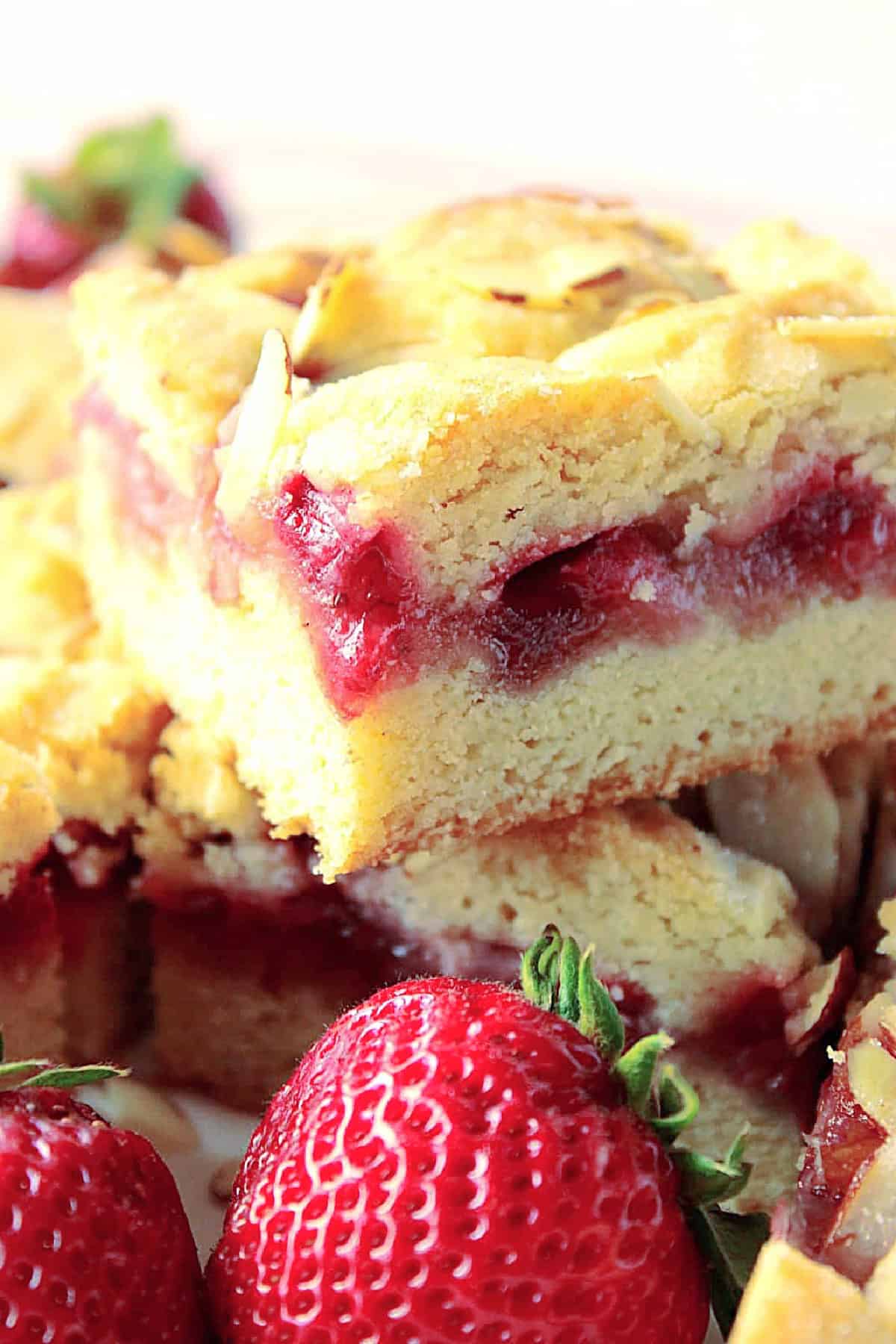 A close up side view of the inside of a strawberry cobbler bar with a layer of strawberry filling.