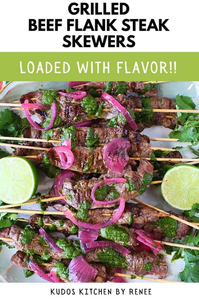 A platter filled with beef flank steak skewers topped with cilantro chimichurri and pickled red onions.