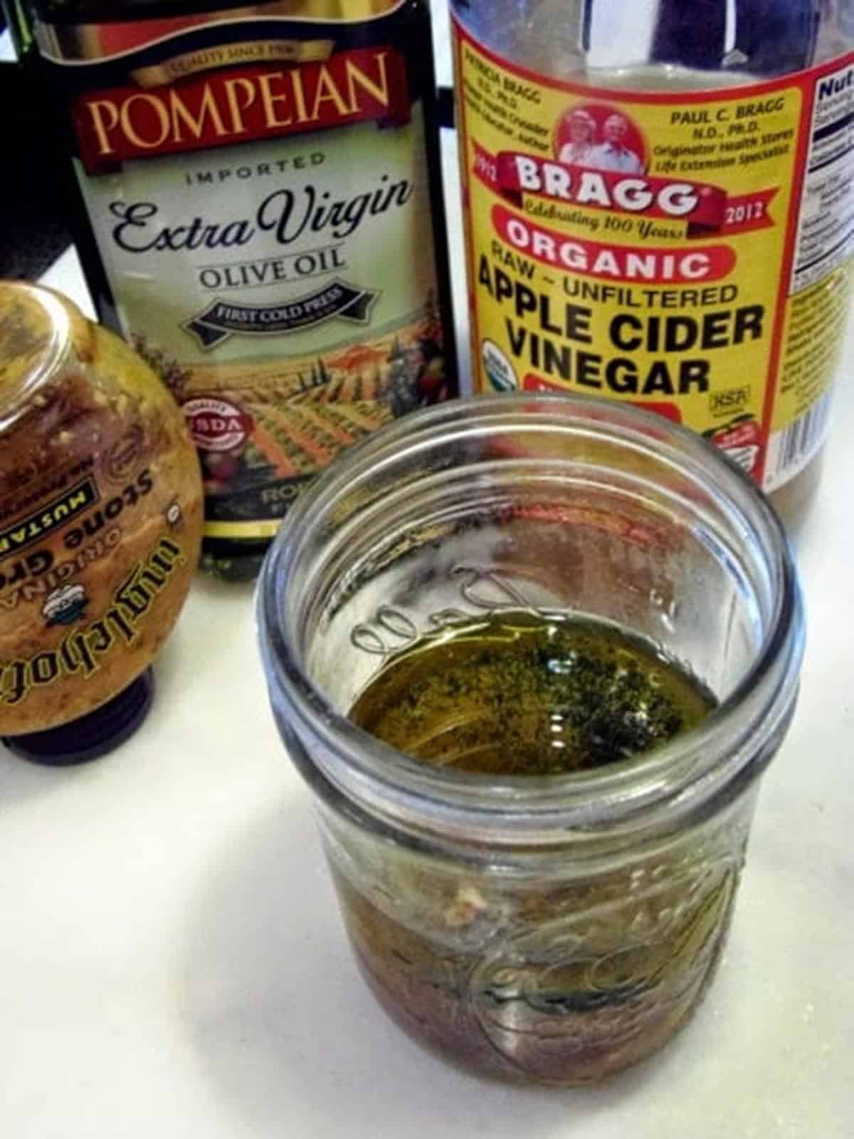 A mason jar with vinegar, olive oil, whole grain mustard to make a German potato salad dressing.