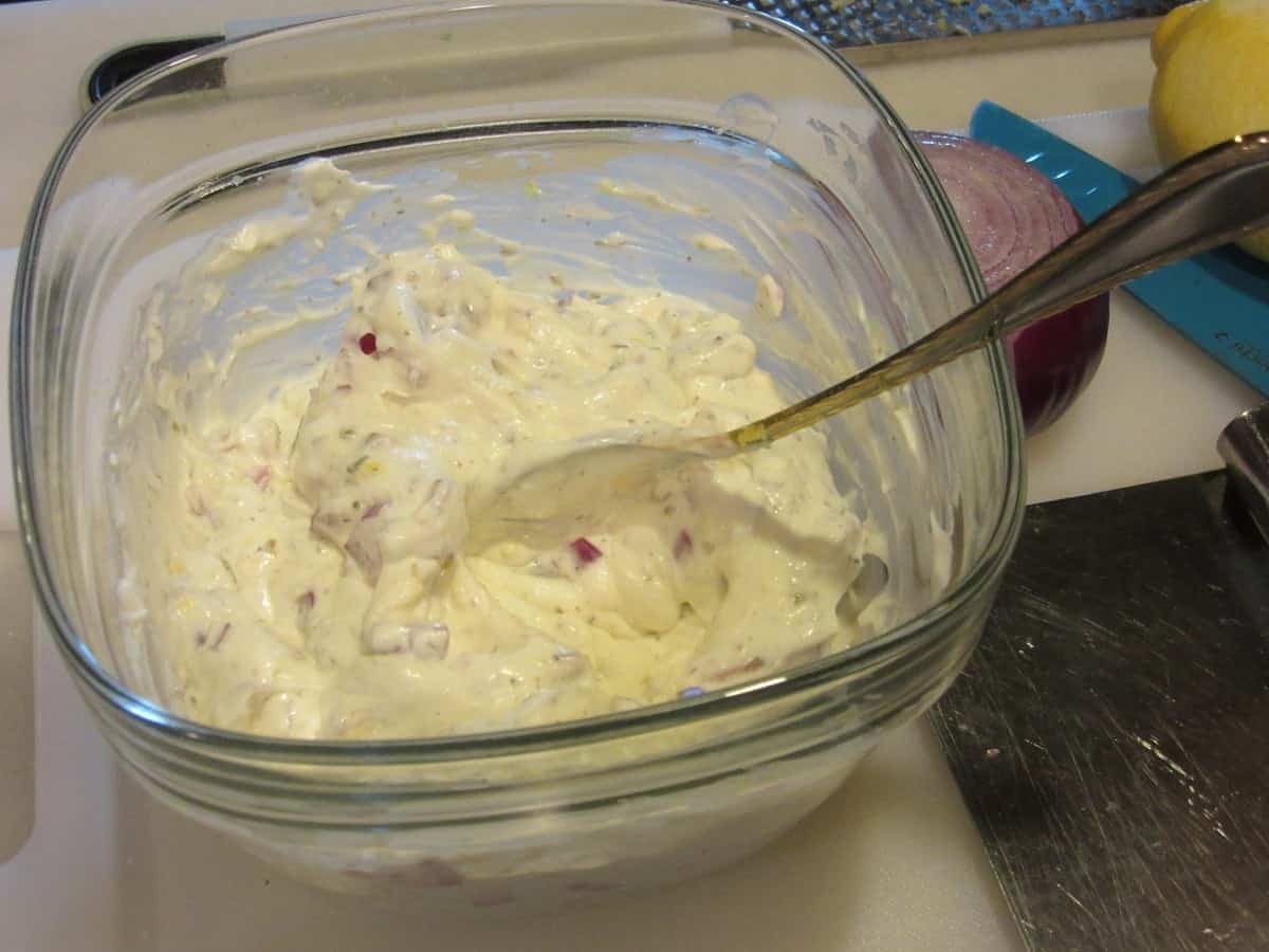 A glass bowl filled with homemade Greek tzatziki sauce along with a spoon.