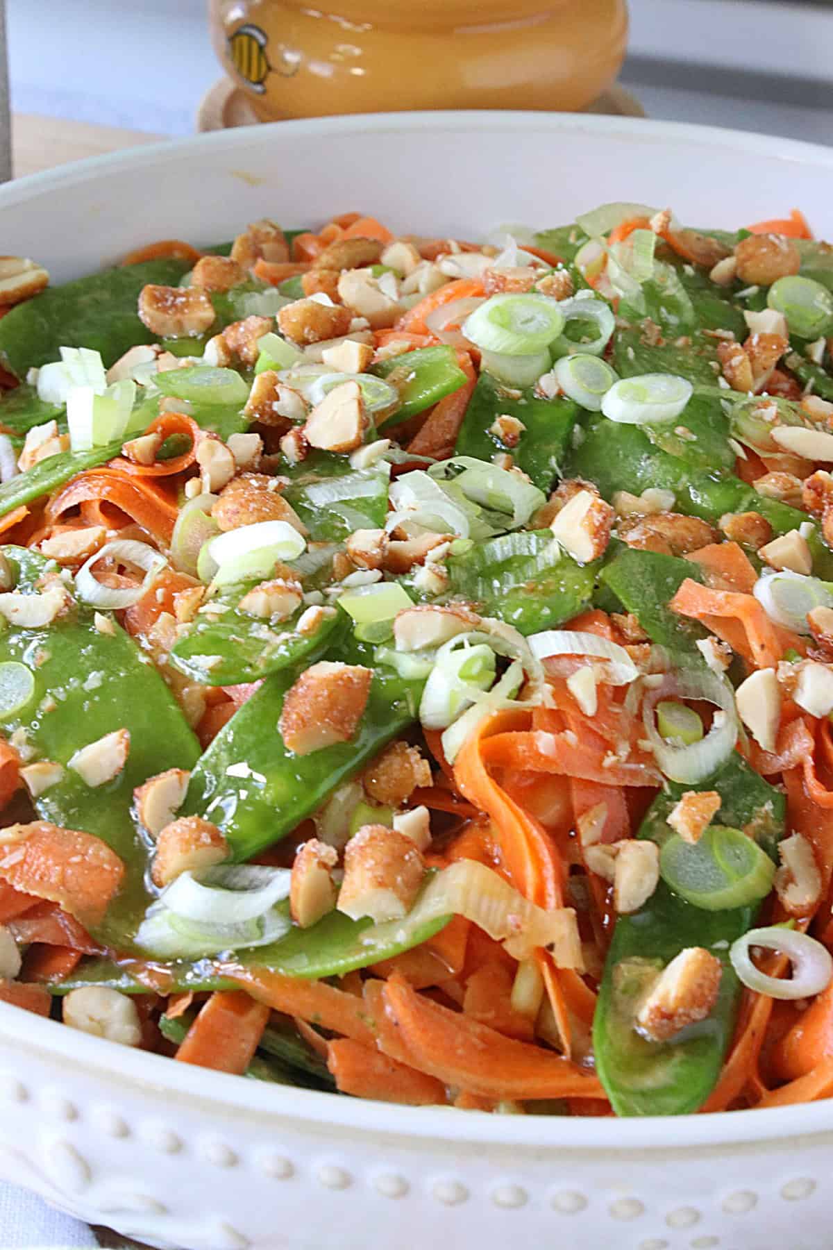 Shredded carrots and green peas and scallions in a bowl as a chilled side dish.