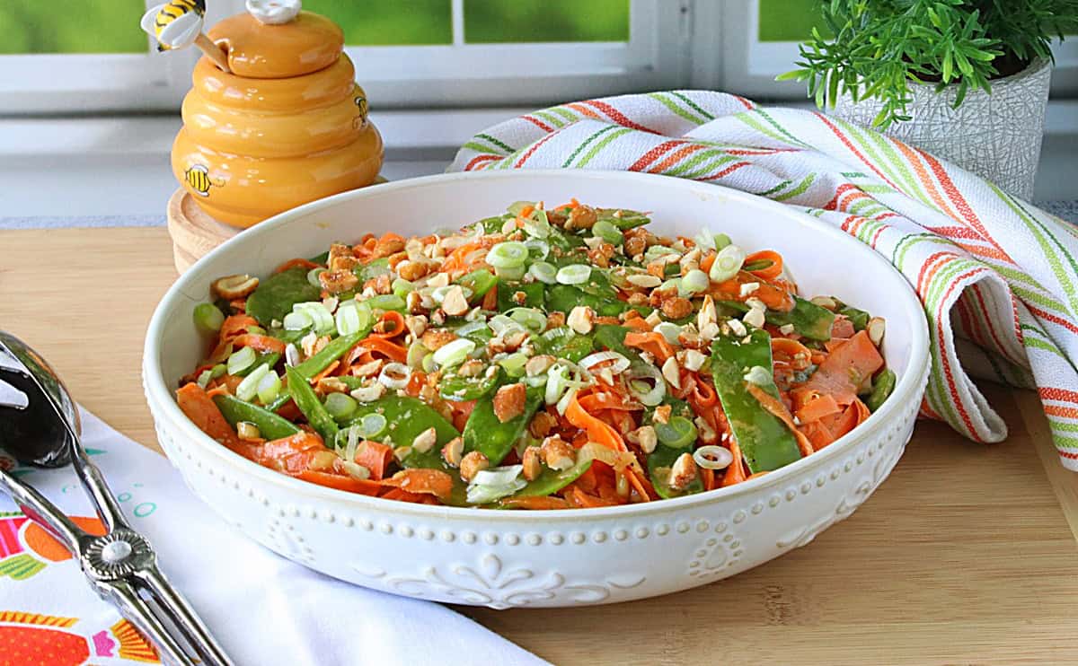 A colorful chilled side dish of orange and green carrots and snow peas.