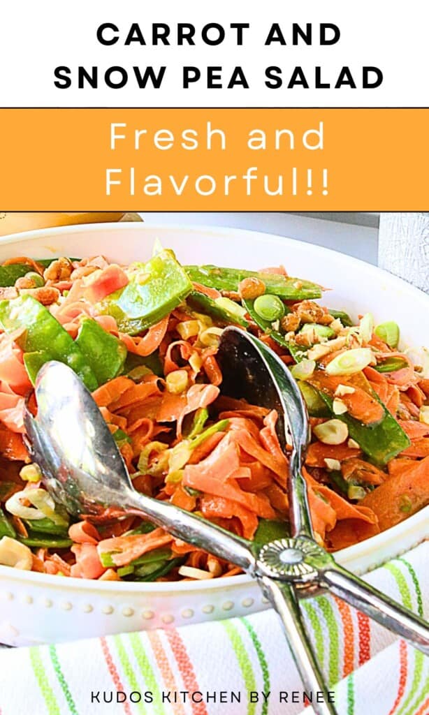 A pair of silver tongs in a bowl of bright orange shredded carrots and green snow pea side dish.