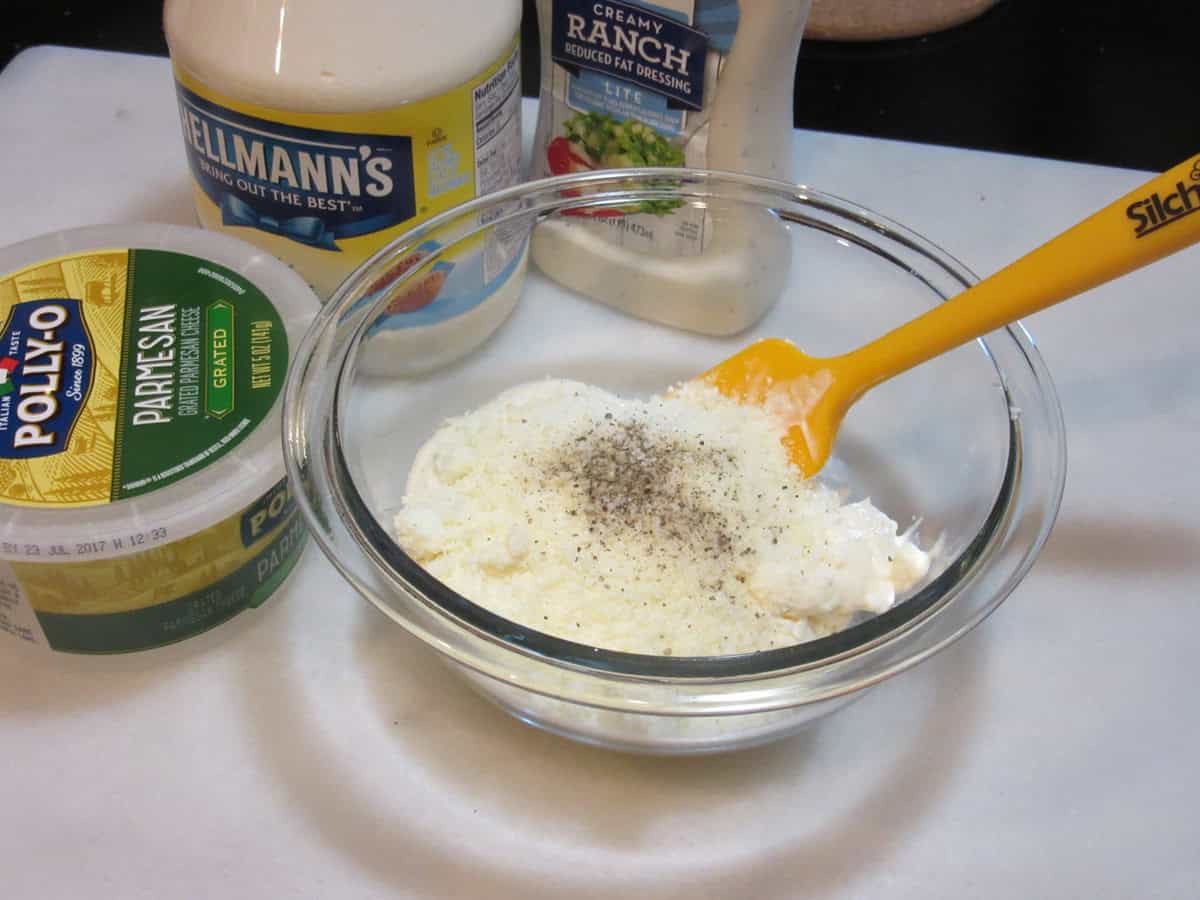 Salt and pepper in a bowl with mayo and grated Parmesan cheese.