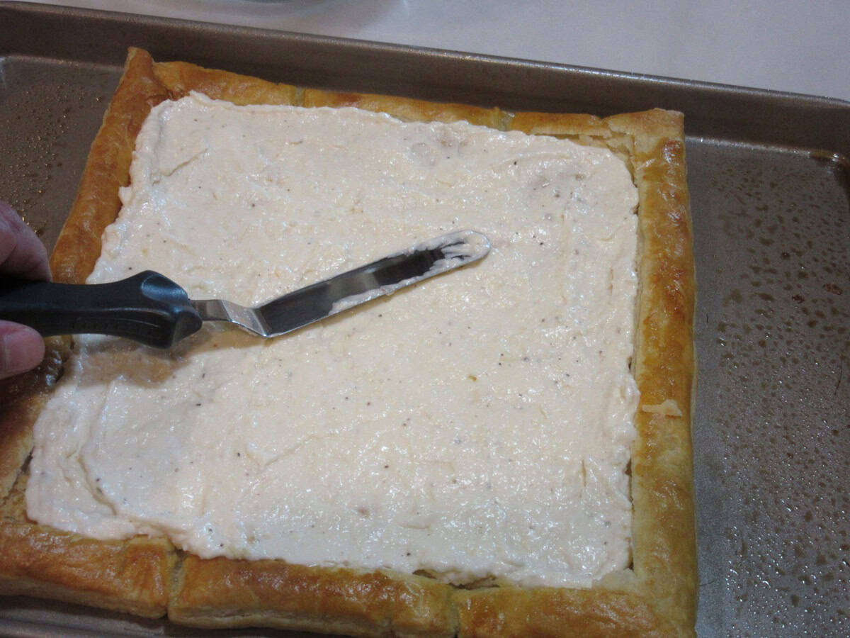 A full layer of filling inside a square of baked puff pastry dough to make a savory appetizer.