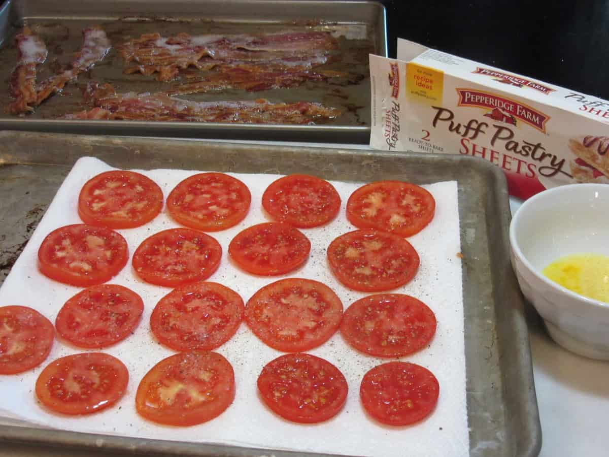 Salted and peppered tomato slices on a paper towel for making a savory tart.