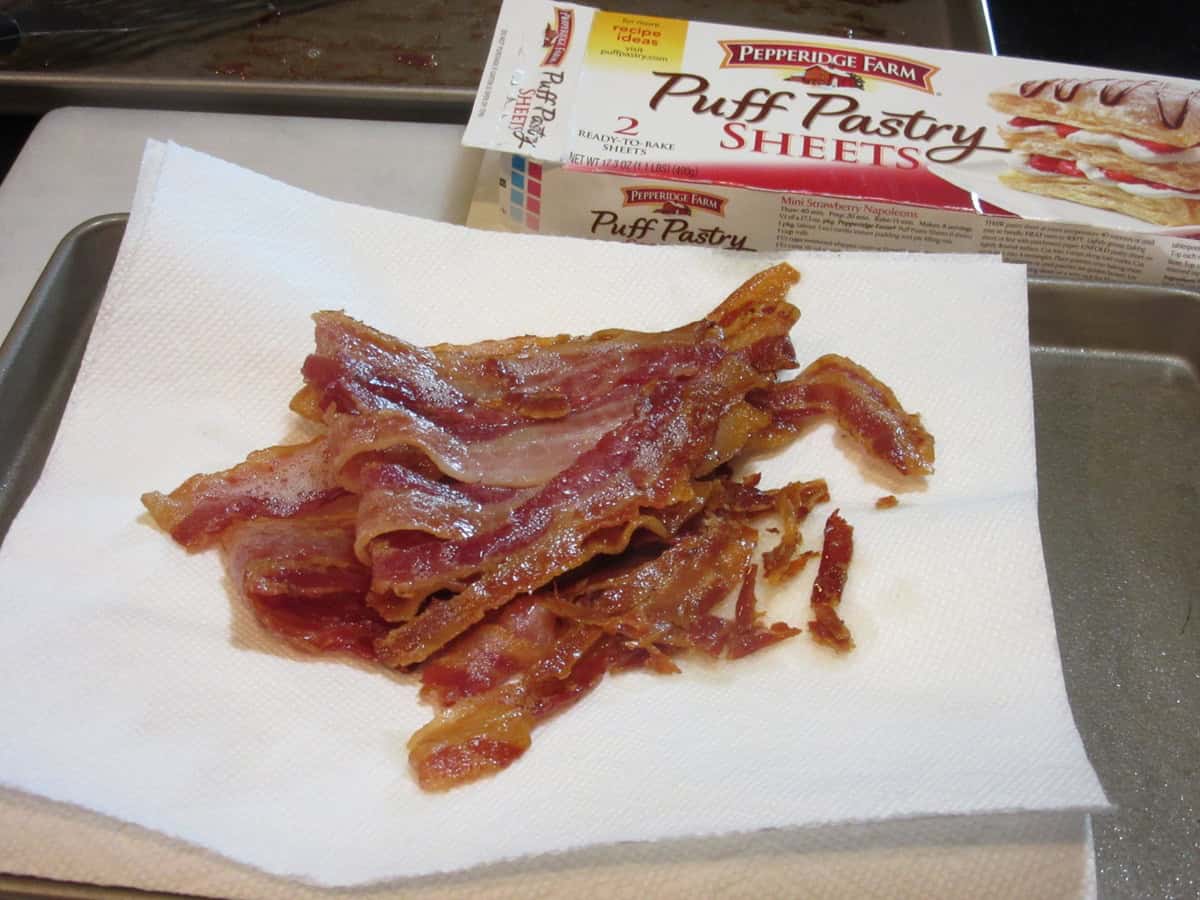 Cooked bacon slices draining on a paper towel.