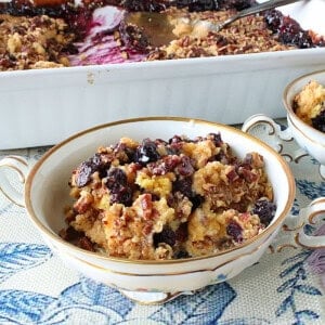 A pretty dish with a serving of cake mix blueberry crisp on a blue and white tablecloth.