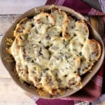 A round casserole dish filled with baked, cheese-topped French onion stuffed shells.