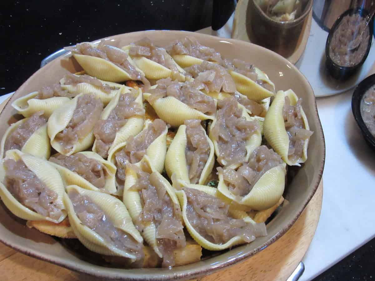 Red wine cooked onions stuffed into jumbo pasta shells in a baking dish.
