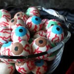 Blue, brown, and green eyeball gumballs in a glass bowl for Halloween.