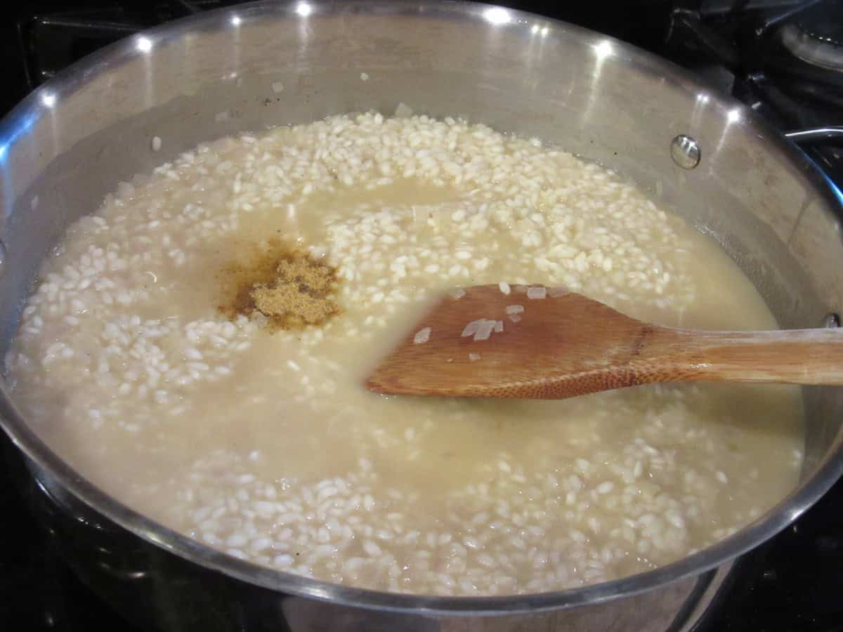 Old bay seafood seasoning added to a skillet with chicken broth and arborio rice.