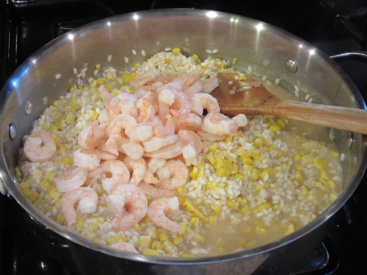 Small cooked salad shrimp in a skillet with sweet corn risotto.