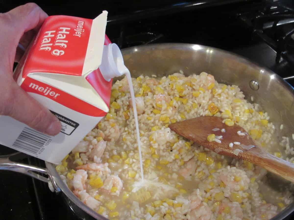 Half and half being added into a skillet with creamy risotto.