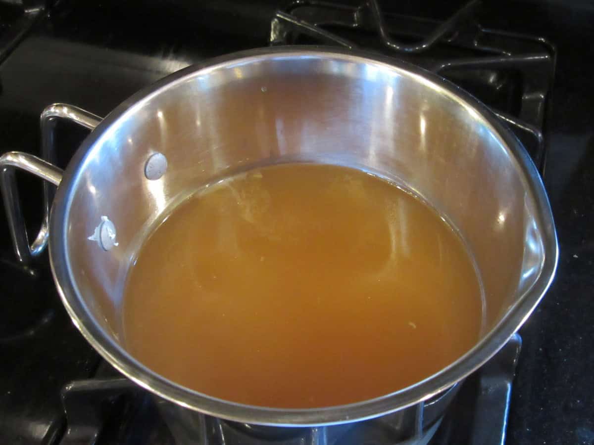 Chicken broth in a small saucepan on the stovetop.